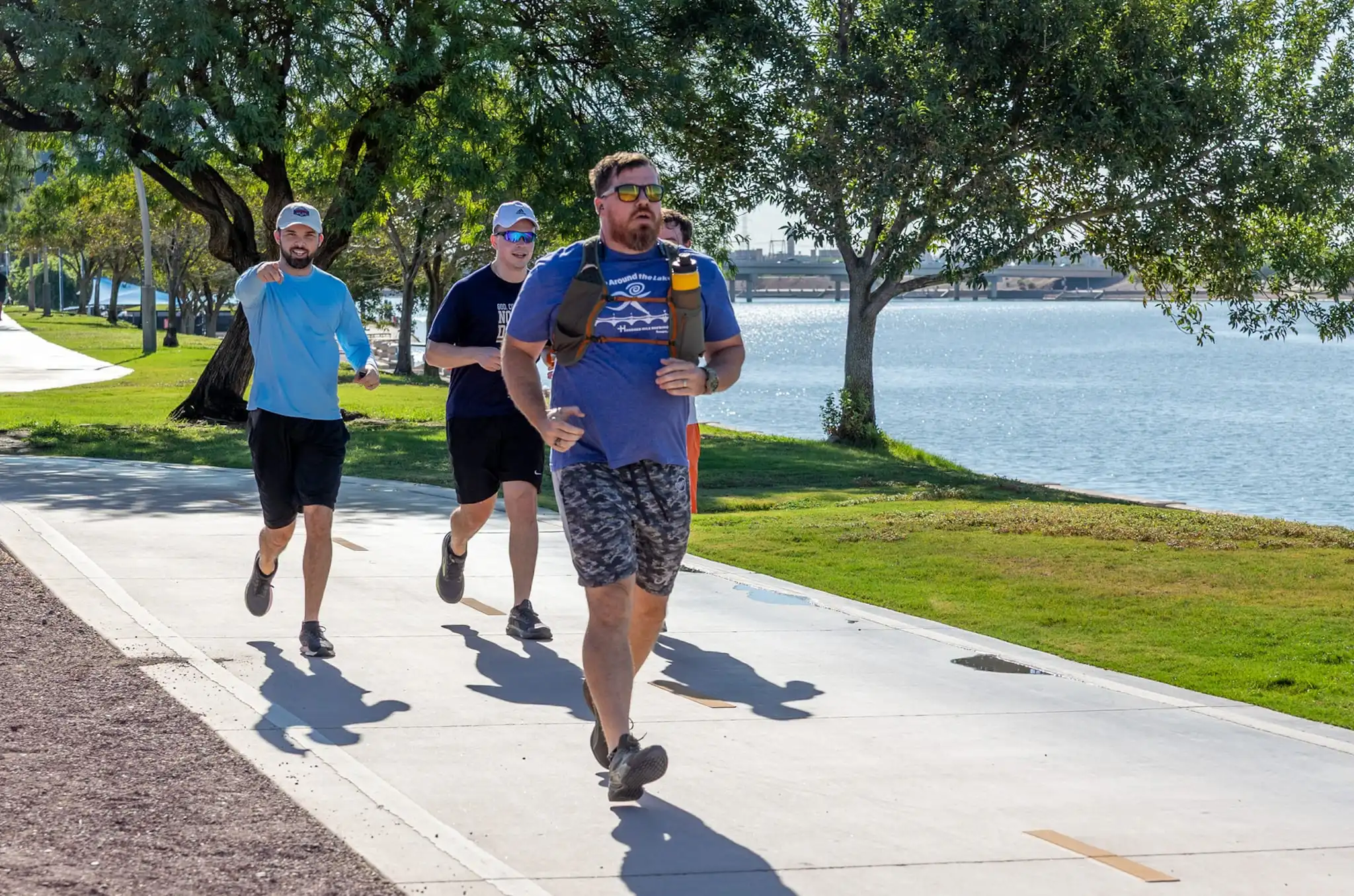 Runners on the Tempe Town Lake path, with the lake and a bridge behind them.