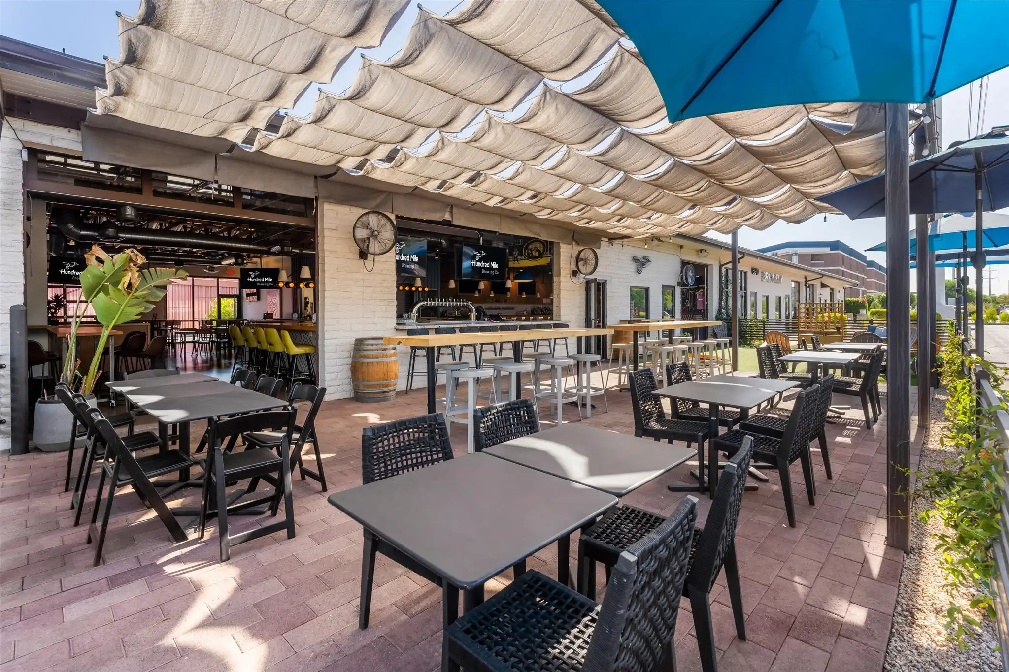 Wide view of the open patio, with string lights overhead and umbrellas over the tables.
